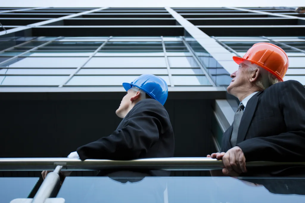 Pourquoi faire appel à un expert d’assuré après un sinistre en entreprise, cadres regardant une façade avec des casques